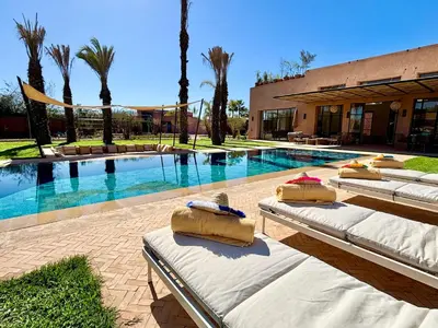 a swimming pool with four beds in front of a building at Palais Kenza in Marrakech