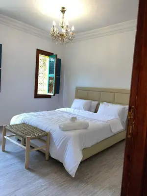 a bedroom with a large white bed with a chandelier at Riad suite for families and groups in Marrakech