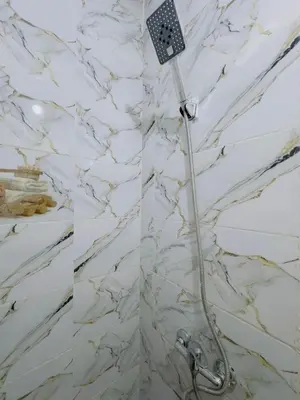 a shower in a bathroom with a white marble wall at Julie Airport Boarding Apartment in Marrakech