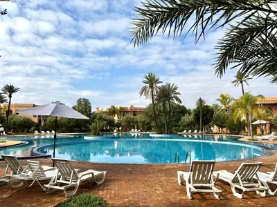 a swimming pool with lounge chairs and palm trees at 2 bedroom palmeraie, pools & 3 terraces in Marrakech