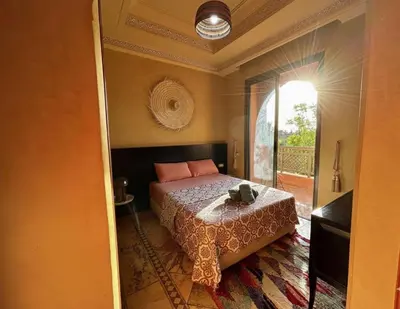 a bedroom with a bed with a table and a window at 2 bedroom palmeraie, pools & 3 terraces in Marrakech