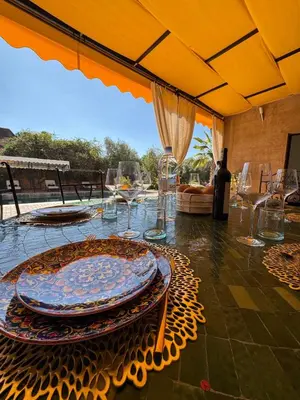 a table with plates and glasses on a patio at Splendide Villa avec piscine in Marrakech