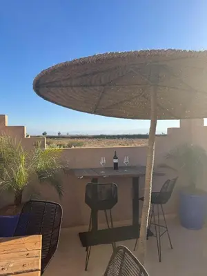 a table and chairs under an umbrella on a patio at Splendide Villa avec piscine in Marrakech