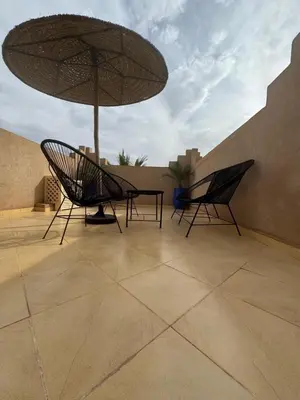 two chairs and a table with an umbrella on a patio at Splendide Villa avec piscine in Marrakech