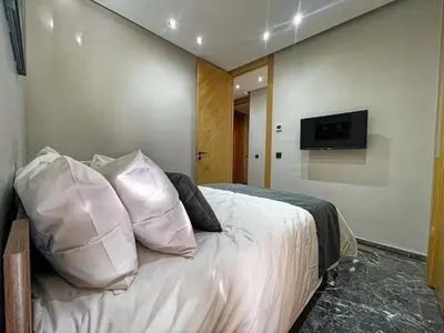 a bedroom with a bed with white pillows and a tv at High-End Cozy and Modern Studio in Marrakech
