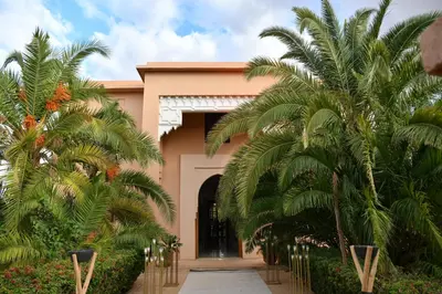 a building with palm trees in front of it at Villa Dar zitoune in Marrakech