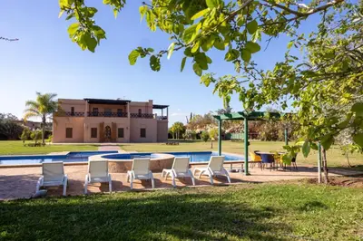 a group of chairs and a table in front of a pool at Villa Dar zitoune in Marrakech