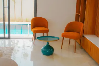 two chairs and a table in a room with a pool at Villa Emeraude 15 minutes du centre in Marrakech