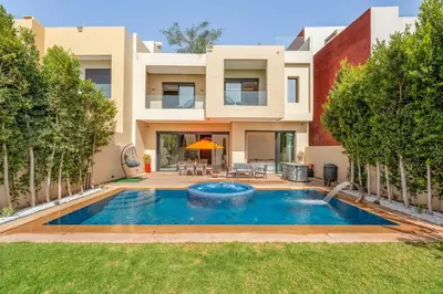 a villa with a swimming pool in front of a house at Villa cancun resort Luxury Spa-cinéma & jacuzzi in Marrakech