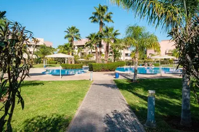 a resort with two swimming pools and palm trees at Elegant Appartement Piscine Golf et Wifi in Marrakech