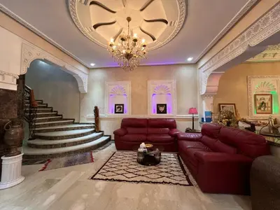 a living room with a red couch and a chandelier at Comfort and Style in the Heart of the City - Villa T in Marrakech