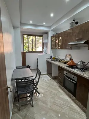a kitchen with a table and a table and chairs at Appartement moderne et chic in Marrakech