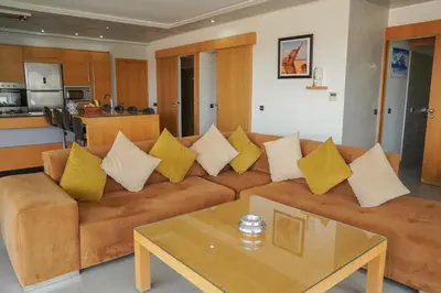 a living room with a brown couch with yellow pillows at Appartement rooftop avec piscine , jacuzzi & fibre Noria Golf in Marrakech