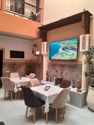 a restaurant with tables and chairs and a large screen at Riad GALFANE in Marrakech