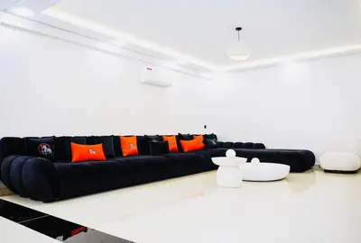 a black couch in a white room with orange pillows at Vaste duplex neuf modernes et raffiné in Marrakech