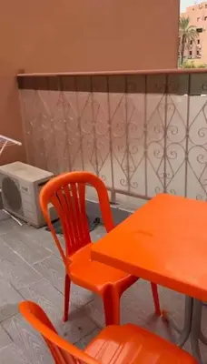 an orange chair and a table and a microwave at 2-bedroom flat in Gueliz in Marrakech