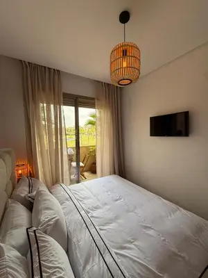 a bedroom with a white bed and a chandelier at Appartement cosy pour 4 personnes in Marrakech