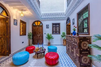 a living room with blue and red chairs and a table at Riad La Perle Bleue Marrakech in Marrakech