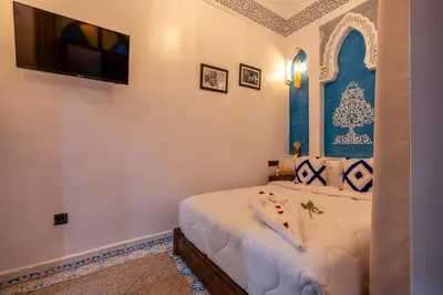 a bedroom with a bed with a tv on the wall at Riad La Perle Bleue Marrakech in Marrakech
