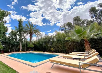 a pool with lounge chairs and a palm tree at Dar El Hana 4 Bedroom Villa in Marrakech