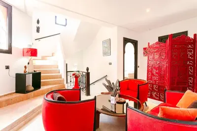 a living room with red chairs and stairs at Villa Atlas Dreams in Marrakech