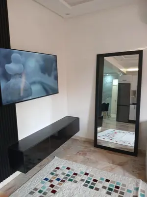 a room with a tv on the wall and a mirror at Cosy appartement Victor Hugo in Marrakech