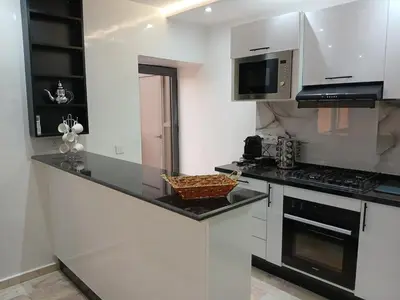 a kitchen with white cabinets and a black counter top at Cosy appartement Victor Hugo in Marrakech