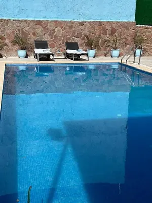two laptops sitting on chairs next to a swimming pool at villa ourika in Marrakech