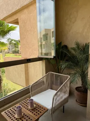 a balcony with a chair and a table and a window at Appartement cosy pour 4 personnes in Marrakech