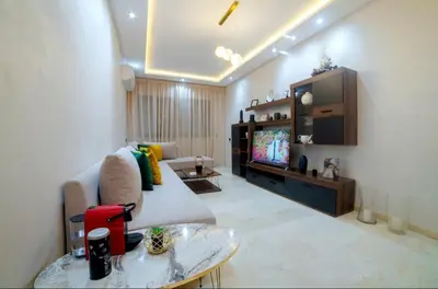 a living room with a couch and a tv at Magnifique appartement avec piscine à Gueliz in Marrakech