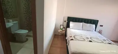 a bedroom with a bed with a green headboard and a toilet at Magnifique appartement avec piscine à Gueliz in Marrakech