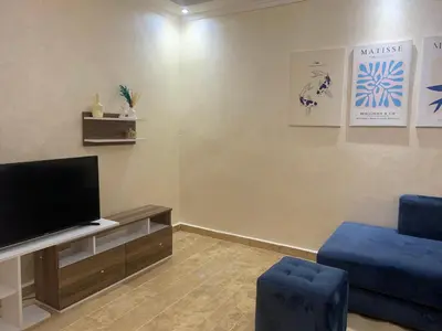 a living room with a tv and a blue chair at Cosy gem in the heart of marrakech in Marrakech