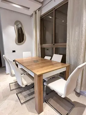 a dining room table with white chairs and a mirror at Prestigia Argane Jubaea Marrakech in Marrakech