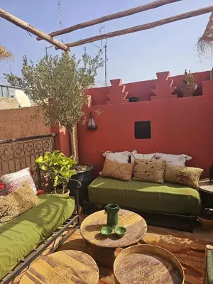 a patio with two green couches and tables at Riad Rose Jade Marrakech in Marrakech