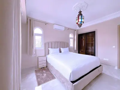 a white bedroom with a large bed and a chandelier at New! Duplex Annakhil , Calme et proximité centre in Marrakech