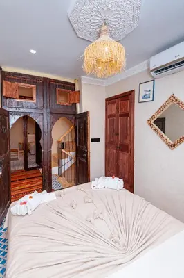 a bedroom with a large bed and a chandelier at Riad Akkioui in Marrakech