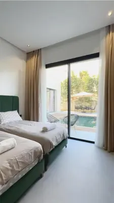 two beds in a bedroom with a view of a pool at Modern Villa Assia in Marrakech