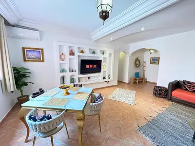 a living room with a table and a tv at Perle Au cœur de Gueliz avec Piscine et 100m2 in Marrakech