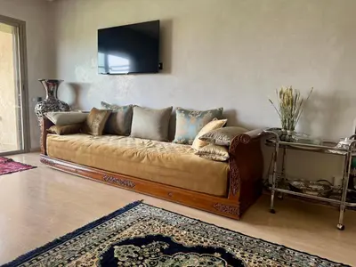 a couch in a living room with a tv on the wall at Marrakech 3 ch piscine et déco artisanale parfait business et famille in Marrakech