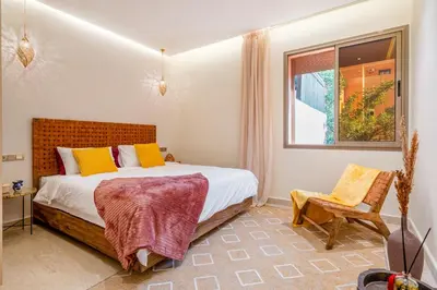 a bedroom with a bed and a chair and a window at Lux & comfort Sunny terrace in Gueliz in Marrakech