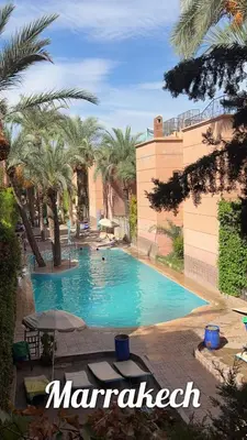 a swimming pool in a resort with palm trees at Riad Marrakech in Marrakech