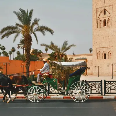 a man riding a horse drawn carriage down a street at Dar Bellaji l Bed & Breakfast in Medina l Rooftop Koutoubia in Marrakech