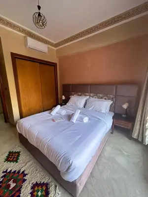 a bedroom with a large bed with white sheets and pillows at Appartement avec piscine in Marrakech