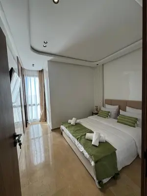 a bedroom with a large white bed with green pillows at Appartement Siniya Cosy à Marrakech in Marrakech