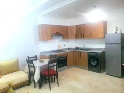 a small kitchen with a table and a refrigerator at Bonheur partagé 2 in Marrakech