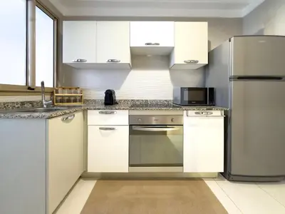 a kitchen with white cabinets and a stainless steel refrigerator at Appartement tout confort à Marrakech avec Piscine et Capacité 4 Personnes in Marrakech