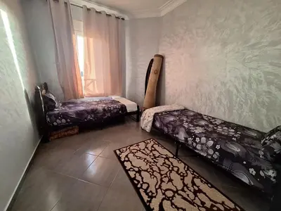 a room with two beds and a chair and a rug at Charming Apartment at Marrakech in Marrakech