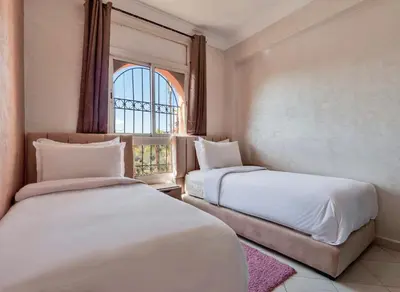 two beds in a room with a window at Modern 3BR Apartment 5 Min from Majorelle Garden in Marrakech