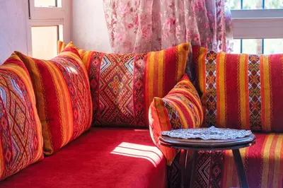 a red couch with colorful pillows and a table at Modern 3BR Apartment 5 Min from Majorelle Garden in Marrakech