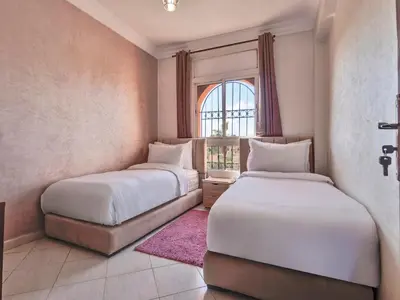 two beds in a room with a window at Modern 3BR Apartment 5 Min from Majorelle Garden in Marrakech